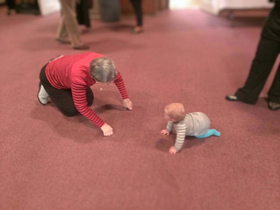 Baby and Senior Crawling on Floor in Church